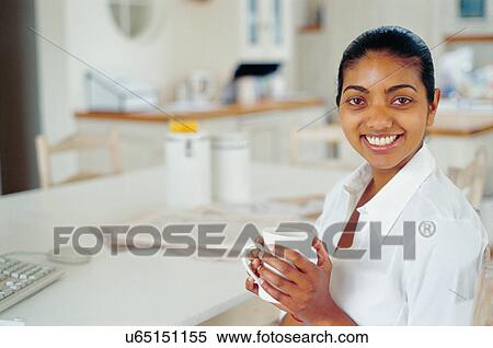 Stock Photography - Woman having cup of coffee at computer. Fotosearch
