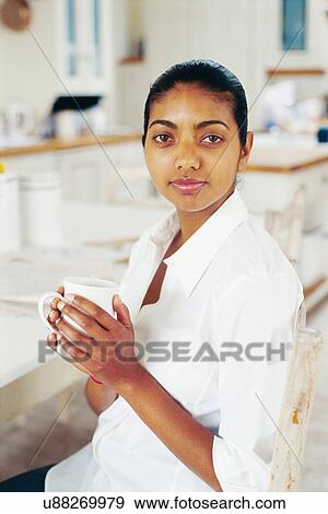 Stock Photo - Woman having cup of coffee in kitchen. Fotosearch