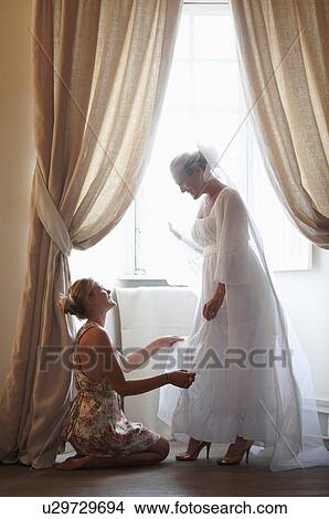 Picture - Woman helping bride get dressed. Fotosearch