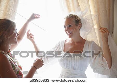 Stock Image - Woman helping bride with veil. Fotosearch