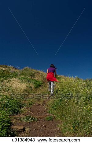 Woman hiking up rural hill View Large Photo Image Stock Photo - Woman hiking up rural hill. Fotosearch