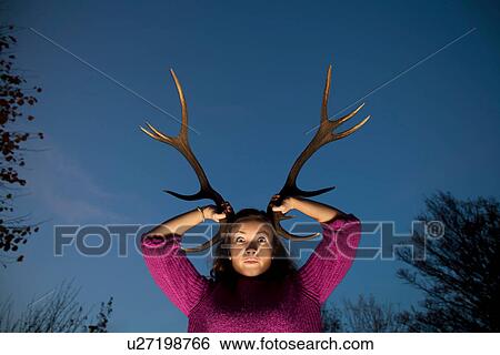 Woman holding antlers on head View Large Photo Image Stock Photograph - Woman holding antlers on head. Fotosearch