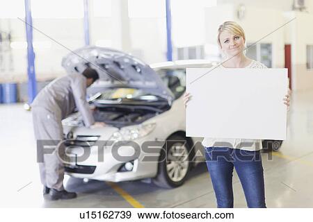 Woman holding blank card in garage View Large Photo Image Stock Photo - Woman holding blank card in garage. Fotosearch
