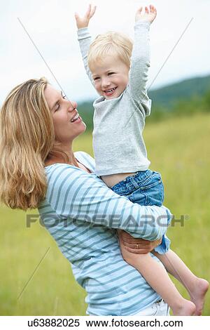 Stock Photography - Woman holding cheering son outdoors. Fotosearch