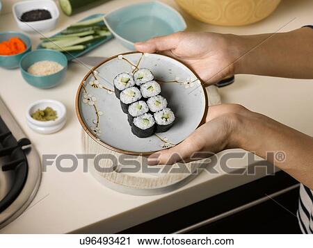 Stock Image - Woman holding plate of sushi. Fotosearch