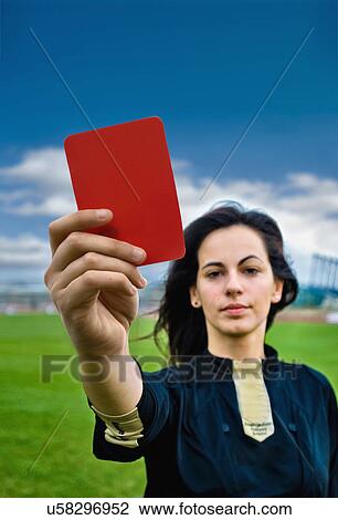 Stock Image - Woman holding red card on soccer pitch. Fotosearch