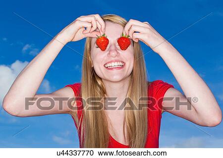 Stock Image - Woman holding strawberries over eyes. Fotosearch
