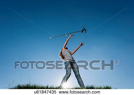 Stock Photography - Woman holding up antenna outdoors. Fotosearch