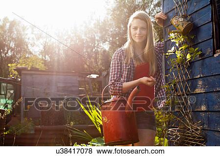 Stock Photo - Woman holding watering can in garden. Fotosearch