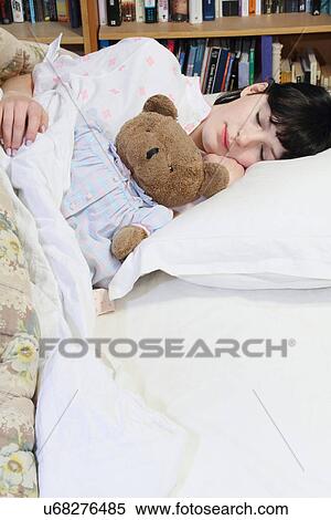 Stock Photography - Woman hugging teddy bear in bed. Fotosearch