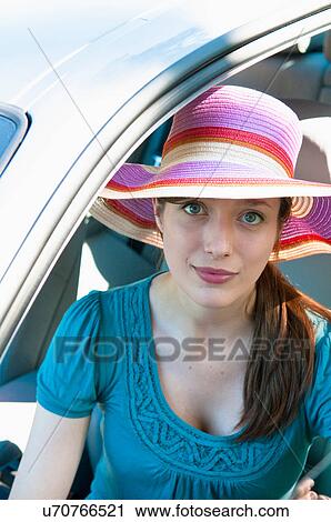 Stock Image - Woman in colorful hat sitting in car. Fotosearch