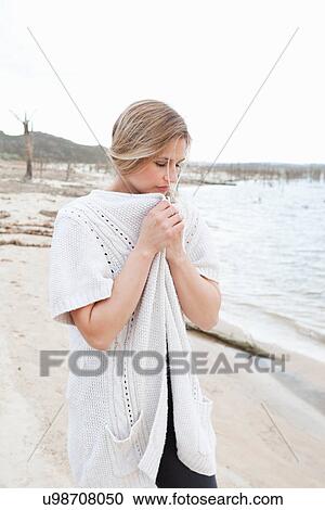 Stock Image - Woman in sweater walking on beach. Fotosearch