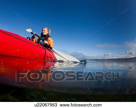 Stock Image - Woman kayaking in still lake. Fotosearch
