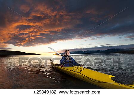 Stock Image - Woman kayaking in still lake. Fotosearch