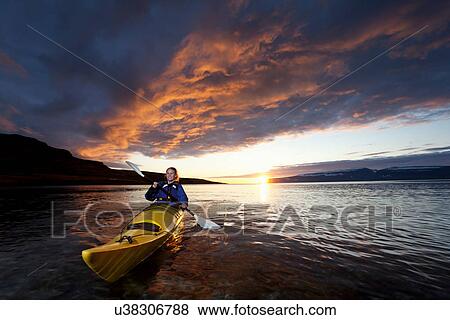 Stock Photo - Woman kayaking in still lake. Fotosearch