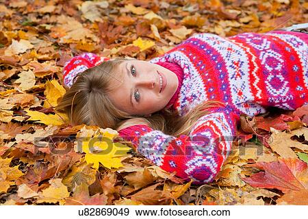 Stock Photo - Woman laying in fall leaves. Fotosearch