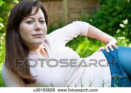 Woman laying in grass in backyard View Large Photo Image Stock Photo - Woman laying in grass in backyard. Fotosearch