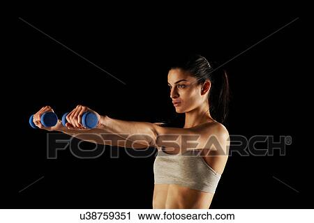 Stock Image - Woman lifting weights during workout. Fotosearch