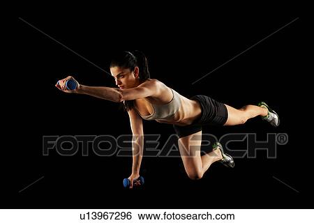 Stock Photograph - Woman lifting weights during workout. Fotosearch