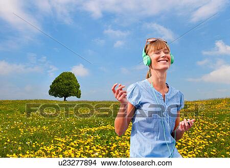 Picture - Woman listening to headphones outdoors. Fotosearch
