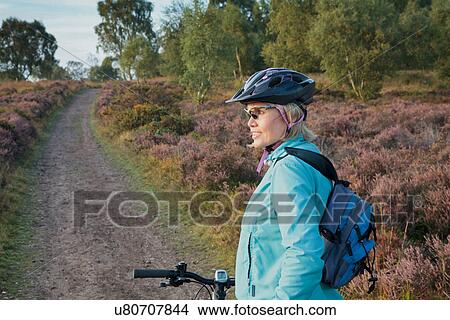 Picture - Woman mountain biking on dirt path. Fotosearch