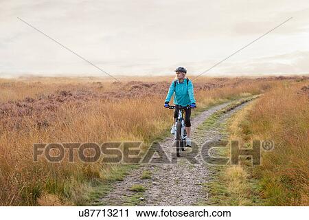 Woman mountain biking on dirt path View Large Photo Image Stock Image - Woman mountain biking on dirt path. Fotosearch