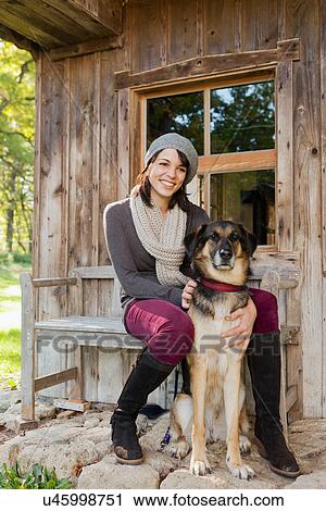 Stock Image - Woman petting dog on porch. Fotosearch