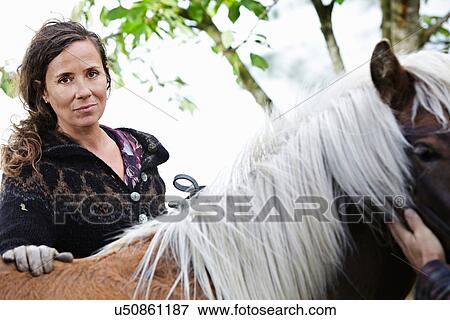 Stock Photo - Woman petting horse outdoors. Fotosearch