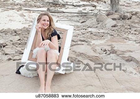 Stock Image - Woman playing in empty picture frame. Fotosearch