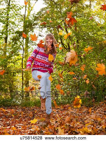Stock Photo - Woman playing in fall leaves. Fotosearch