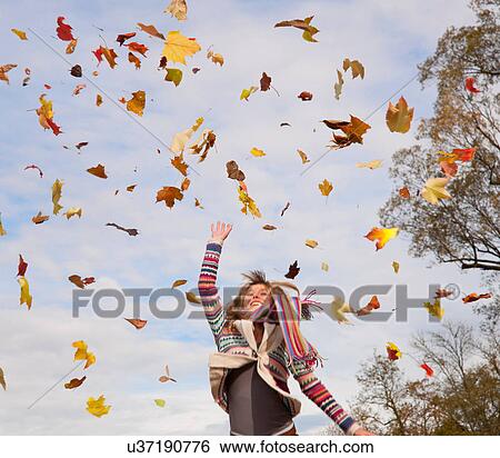 Stock Photograph - Woman playing in fall leaves. Fotosearch
