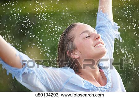 Stock Image - Woman playing in sprinkler. Fotosearch