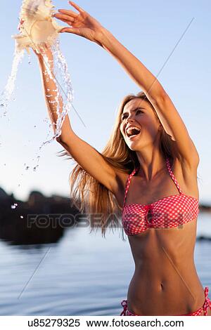 Woman playing with seashell on beach View Large Photo Image Stock Photography - Woman playing with seashell on beach. Fotosearch