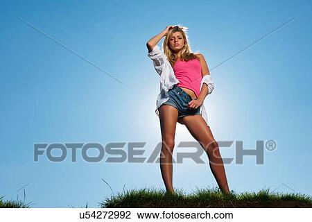 Stock Image - Woman posing on grassy hill. Fotosearch