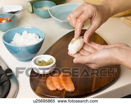 Stock Photography - Woman preparing sushi at table. Fotosearch