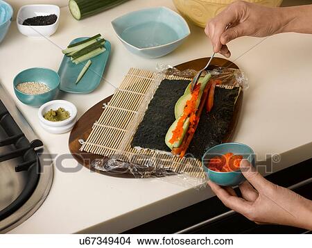 Woman preparing sushi roll at table View Large Photo Image Picture - Woman preparing sushi roll at table. Fotosearch