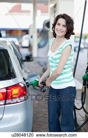 Woman pumping gas into car View Large Photo Image Stock Image - Woman pumping gas into car. Fotosearch