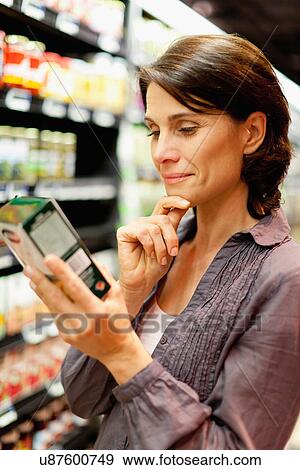 Woman reading box in grocery store View Large Photo Image Stock Photo - Woman reading box in grocery store. Fotosearch