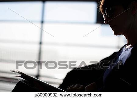 Woman reading magazine in airport View Large Photo Image Stock Image - Woman reading magazine in airport. Fotosearch
