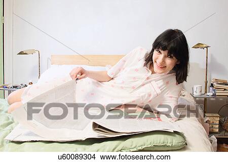 Woman reading newspaper in bed View Large Photo Image Picture - Woman reading newspaper in bed. Fotosearch