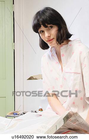 Stock Image - Woman reading newspaper in bed. Fotosearch