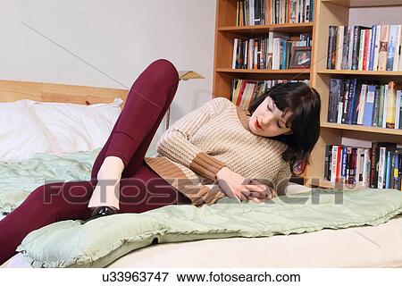 Woman relaxing on bed View Large Photo Image Stock Photo - Woman relaxing on bed. Fotosearch