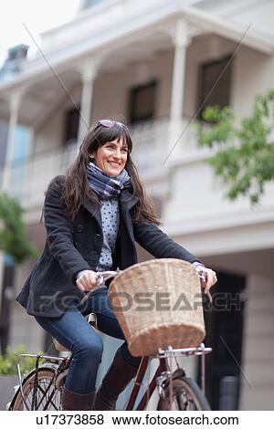 Stock Photo - Woman riding bicycle on city street. Fotosearch
