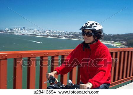Woman riding bike on urban bridge View Large Photo Image Picture - Woman riding bike on urban bridge. Fotosearch