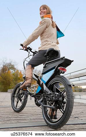 Picture - Woman riding bike on wooden walkway. Fotosearch