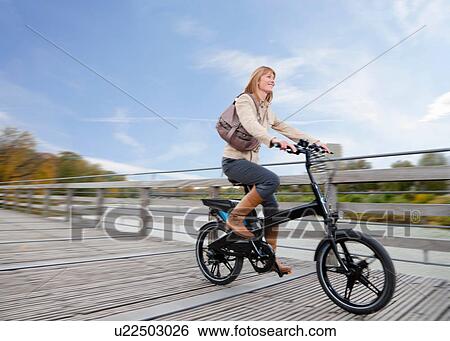 Woman riding bike on wooden walkway View Large Photo Image Stock Photograph - Woman riding bike on wooden walkway. Fotosearch