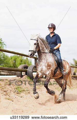 Stock Photo - Woman riding horse in yard. Fotosearch