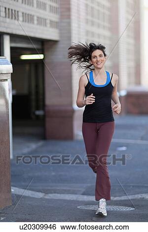 Woman running on city street View Large Photo Image Stock Photograph - Woman running on city street. Fotosearch