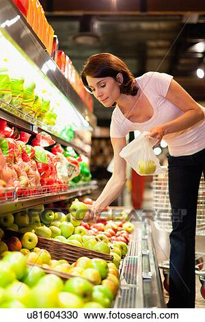 Woman selecting fruit at grocery store View Large Photo Image Stock Image - Woman selecting fruit at grocery store. Fotosearch