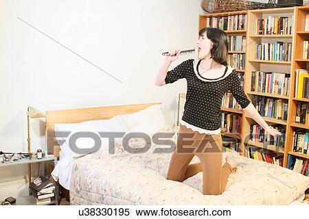 Woman singing into hairbrush on bed View Large Photo Image Stock Photography - Woman singing into hairbrush on bed. Fotosearch